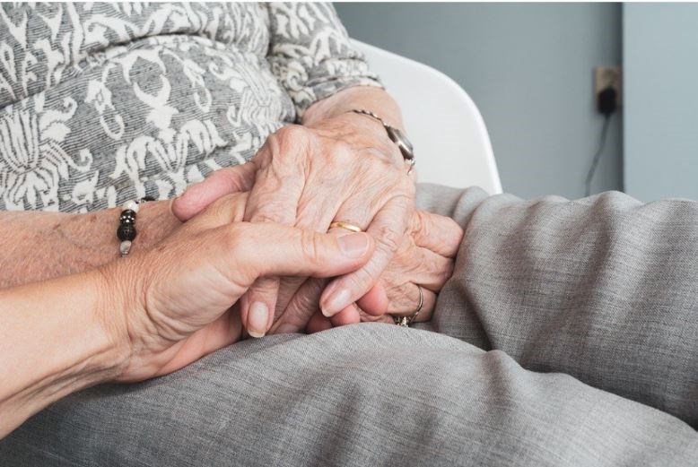 En äldre persons hand håller i annan hand