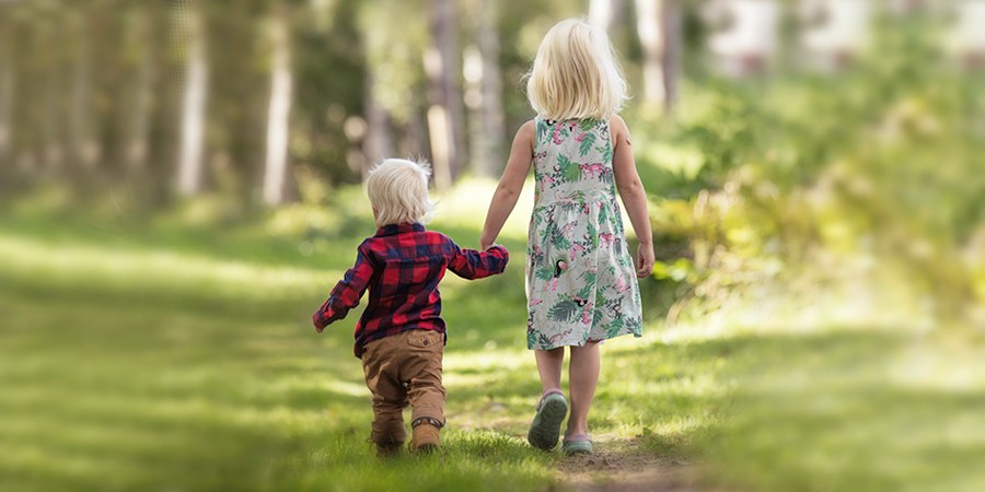 En liten pojke och en flicka gå hand i hand på en sommarstig