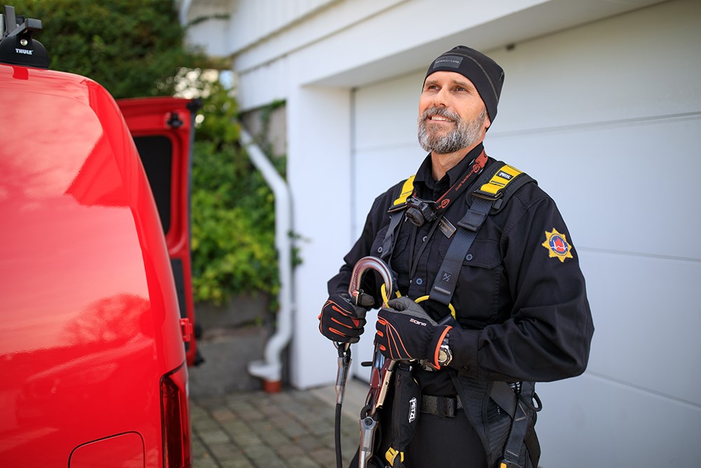 En person i RSG uniform med en säkerhetssele, hen står bredvid en röd bil. 