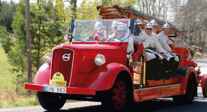 Veteranbrandbil med brandmän i historiska kläder